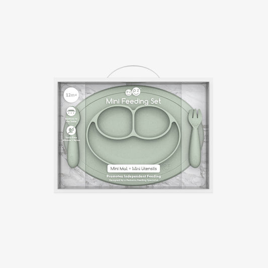 Green mini feeding set with plate, spoon, and fork in packaging on a white background